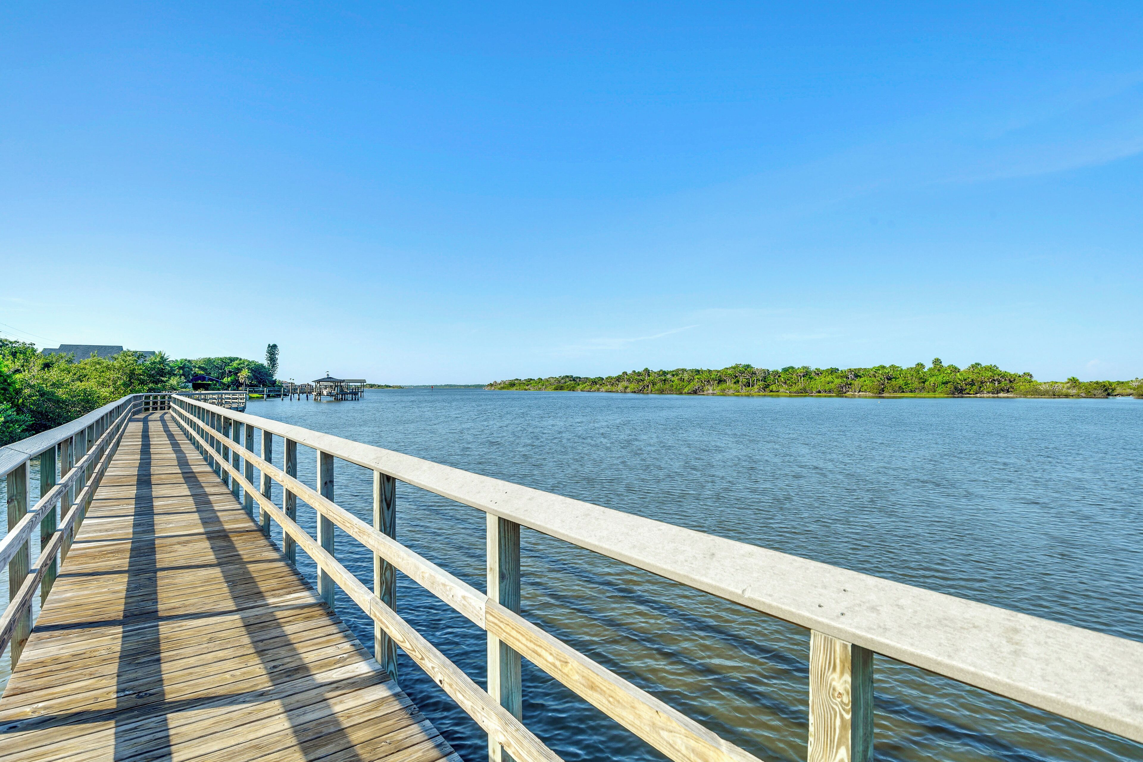 A wooden pier extending into calm water with a clear sky above.