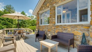 A stone house with a deck featuring outdoor furniture, including chairs and a table.