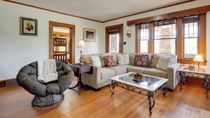 A living room with a sofa, armchair, coffee table, and wooden flooring.
