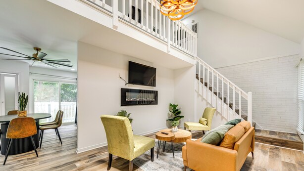 A spacious living area with a high ceiling, a staircase, and a dining area with modern furniture.