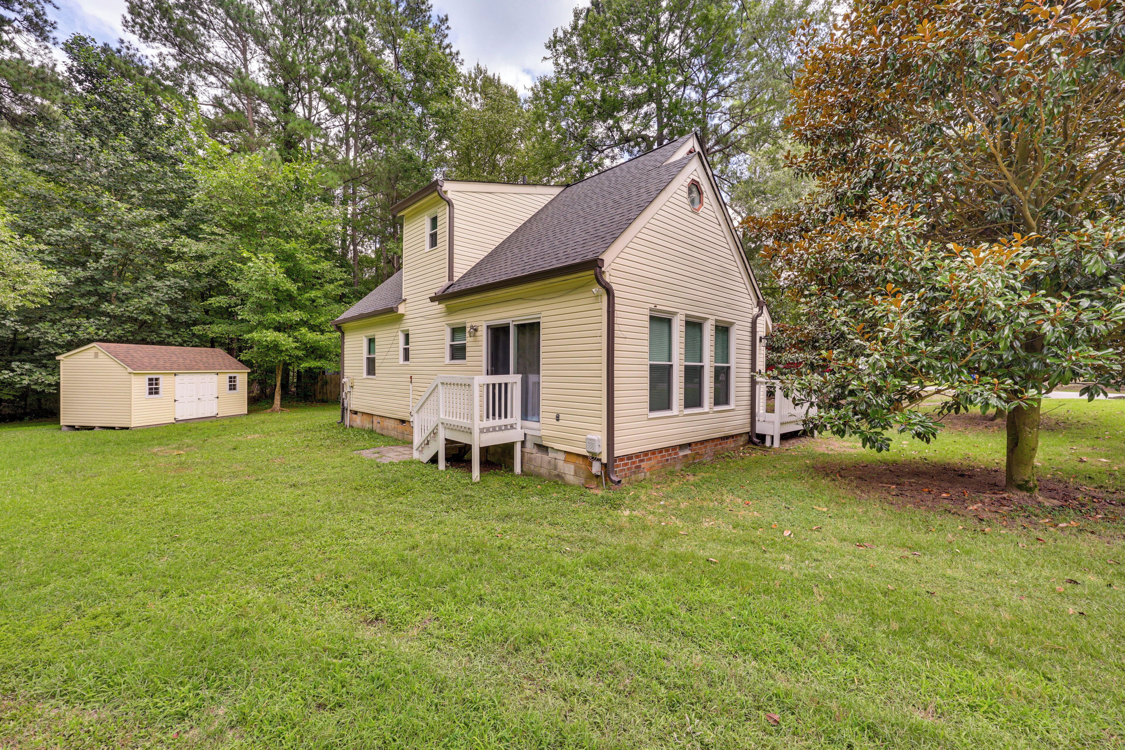 A two-story house with a front porch and a small shed in a grassy yard.