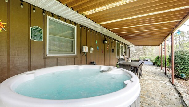 A hot tub under a wooden pergola with a stone pathway leading to a patio area. - Scenic Asheville Area Retreat: Hot Tub & Game Room (Candler)