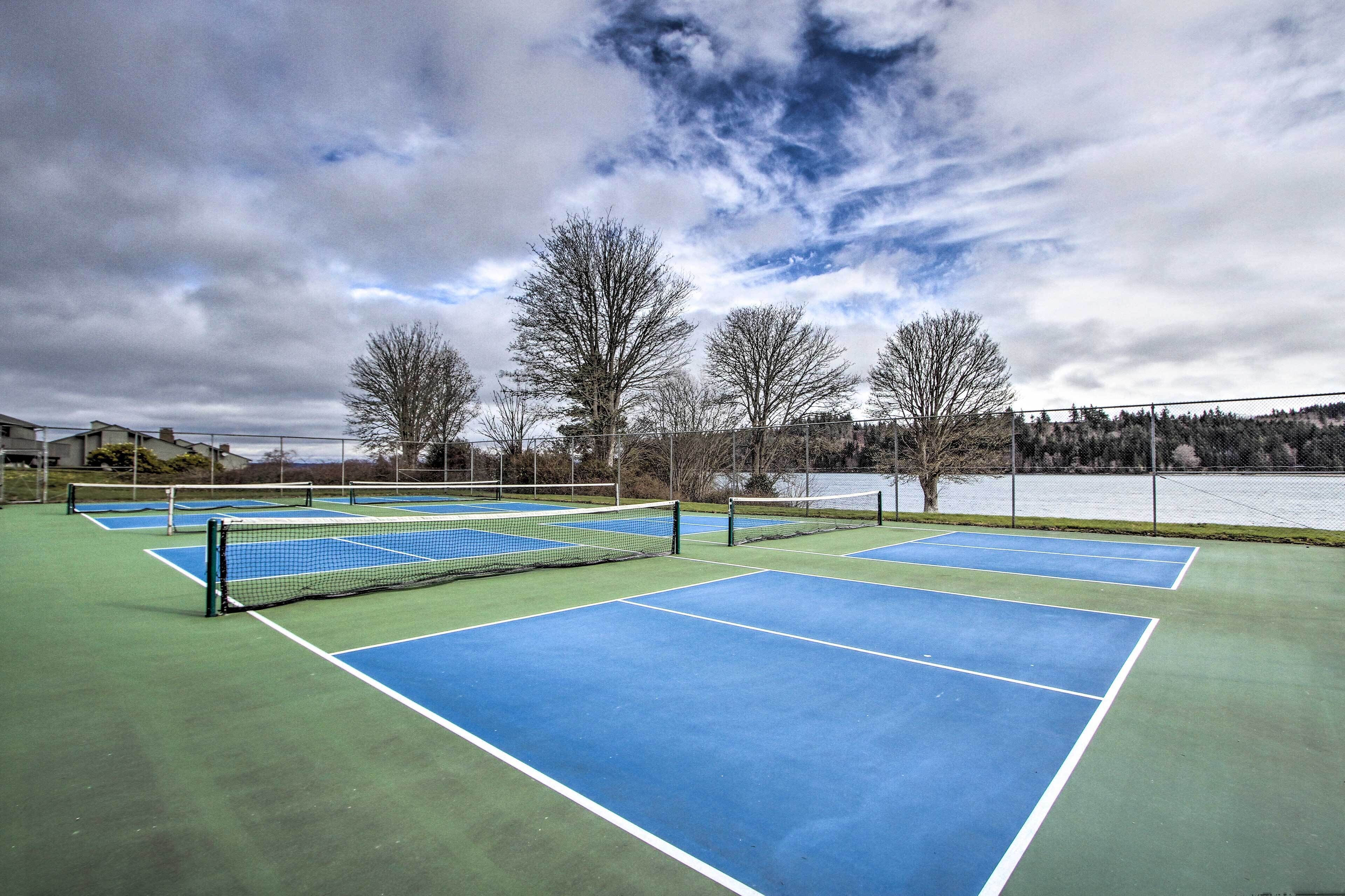 An outdoor tennis court with multiple courts, a net, and a fence.