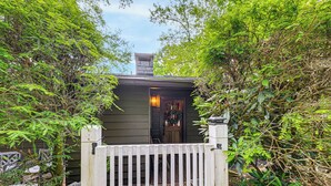 A wooden cabin with a porch, surrounded by dense foliage. - Hike, Fish & Explore: Family Retreat in Highlands (Highlands)