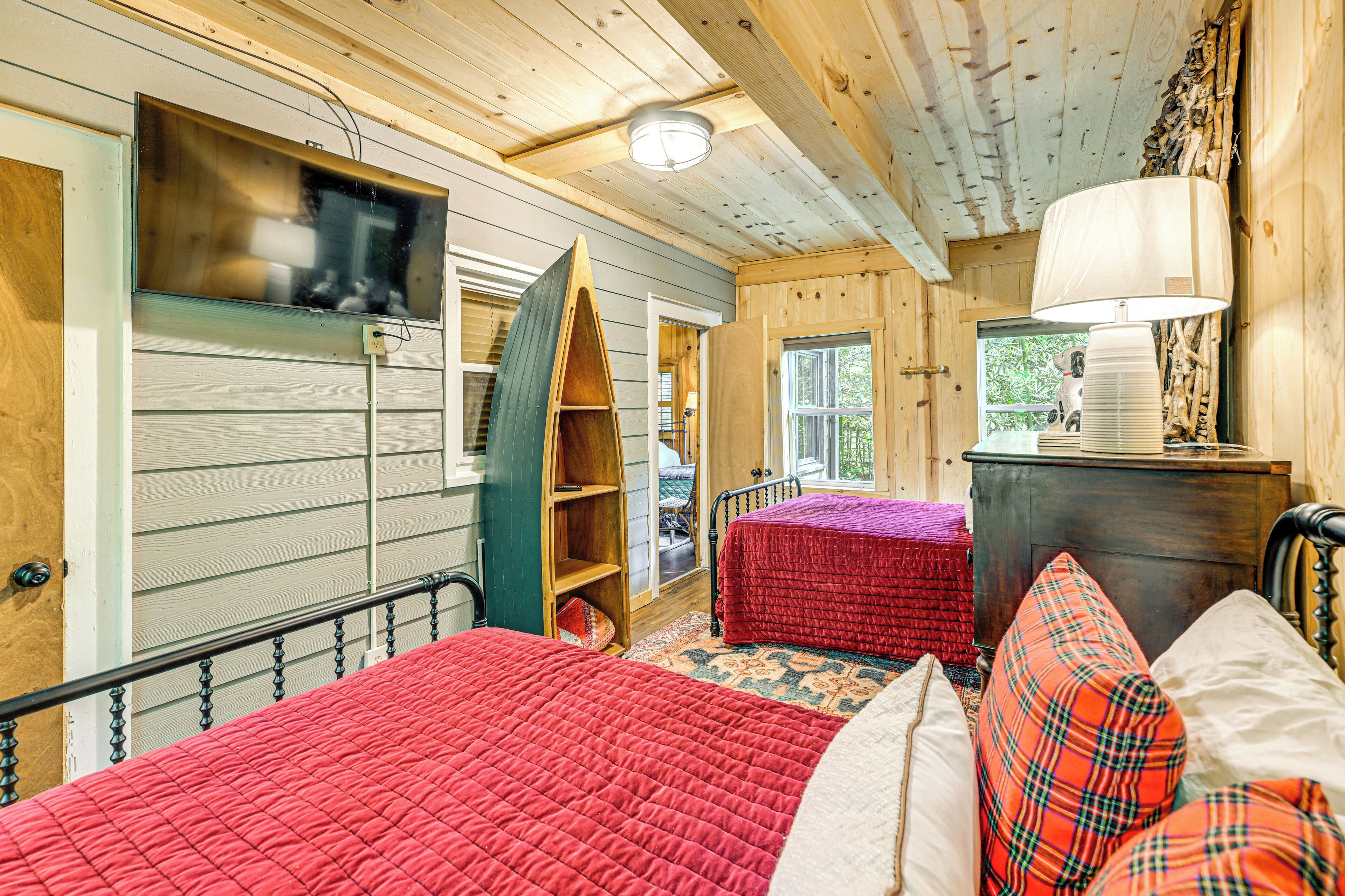 Una habitación acogedora estilo cabaña con dos camas, techo de madera, televisor y cómoda.