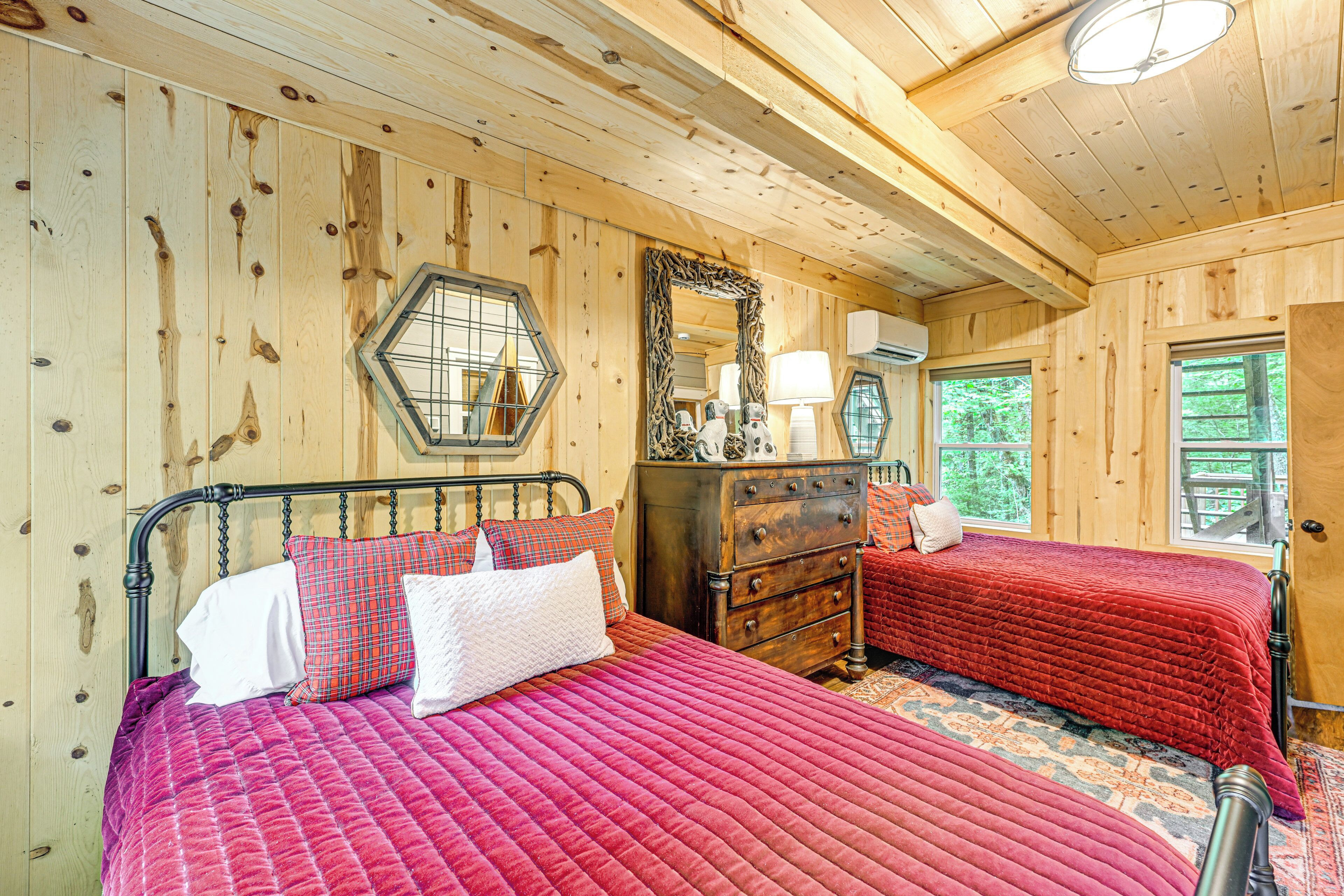 Quarto de cabana de madeira com duas camas, uma cômoda e um espelho.