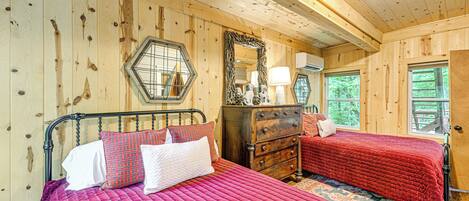 Quarto de cabana de madeira com duas camas, uma cômoda e um espelho.