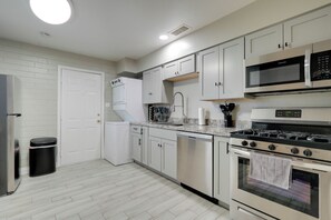 A modern kitchen with white cabinets, stainless steel appliances, and a granite countertop.