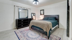 Une chambre à coucher avec un lit, une commode et un miroir.