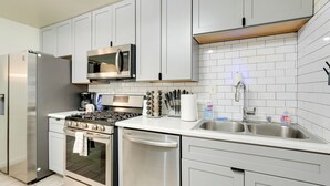 Une cuisine moderne avec des armoires blanches, des appareils en acier inoxydable et un dosseret carrelé.