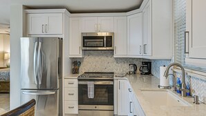 Una cocina moderna con gabinetes blancos, electrodomésticos de acero inoxidable y un salpicadero de baldosas en espiga.