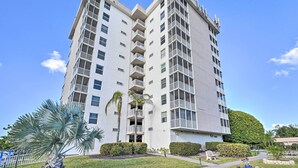 Un edificio de varios pisos con balcones, una palmera y un césped bien cuidado.