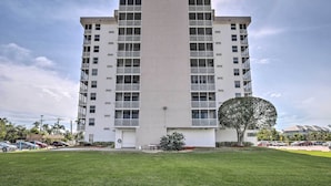 A modern multi-story building with balconies, a flat roof, and a parking area in front. - Walk to Beach: Bonita Springs Gem w/ Pool! (Bonita Springs)