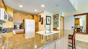 A kitchen with granite countertops, wooden cabinets, a refrigerator, and a sink. - 7 Mi to Disney World: Condo w/ 2 Balconies + Pools (Kissimmee)
