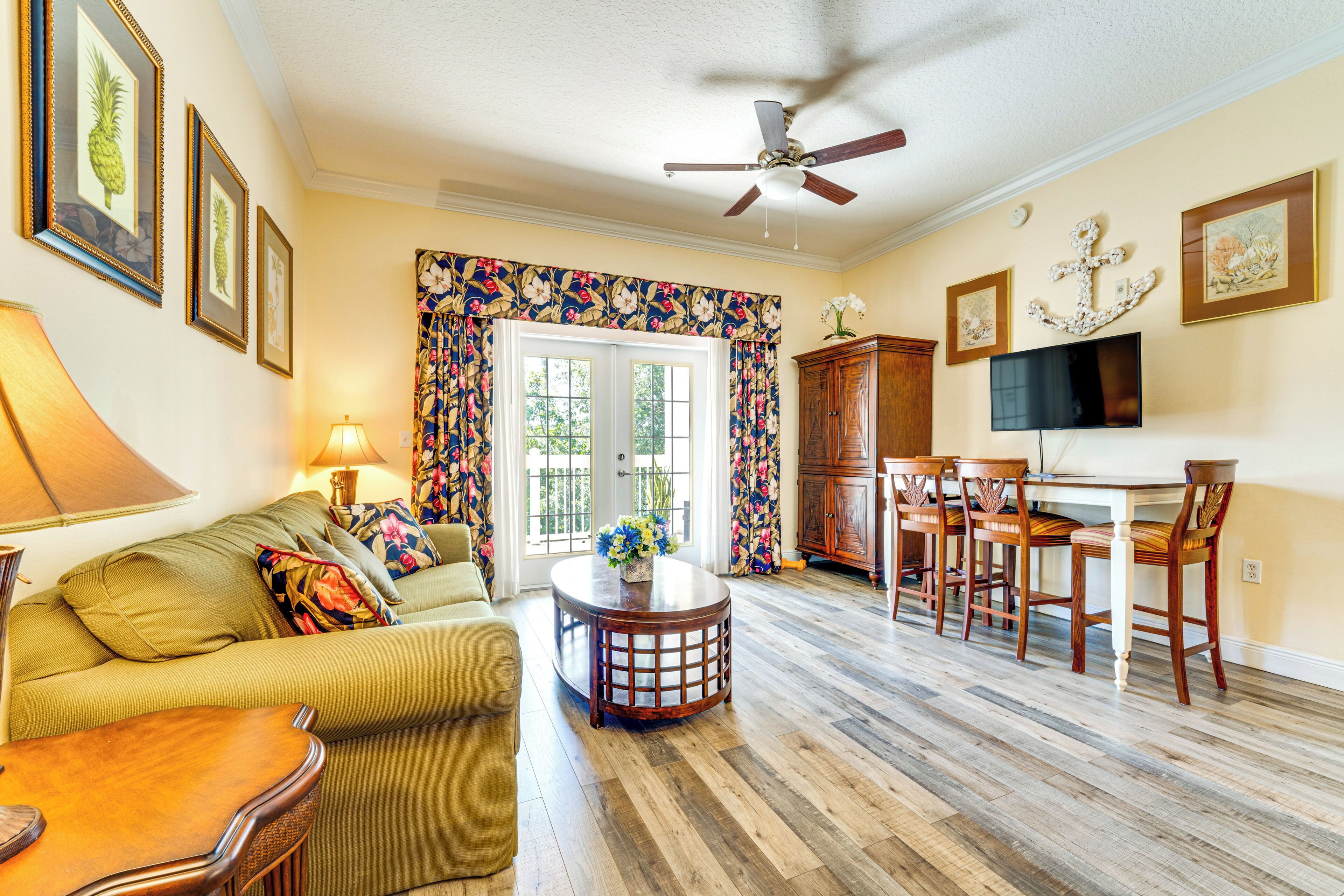 A living room with a sofa, a coffee table, a TV, and a ceiling fan.