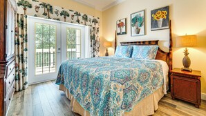 A bedroom with a large bed, a wooden headboard, a nightstand with a lamp, and a window with curtains. - 7 Mi to Disney World: Condo w/ 2 Balconies + Pools (Kissimmee)