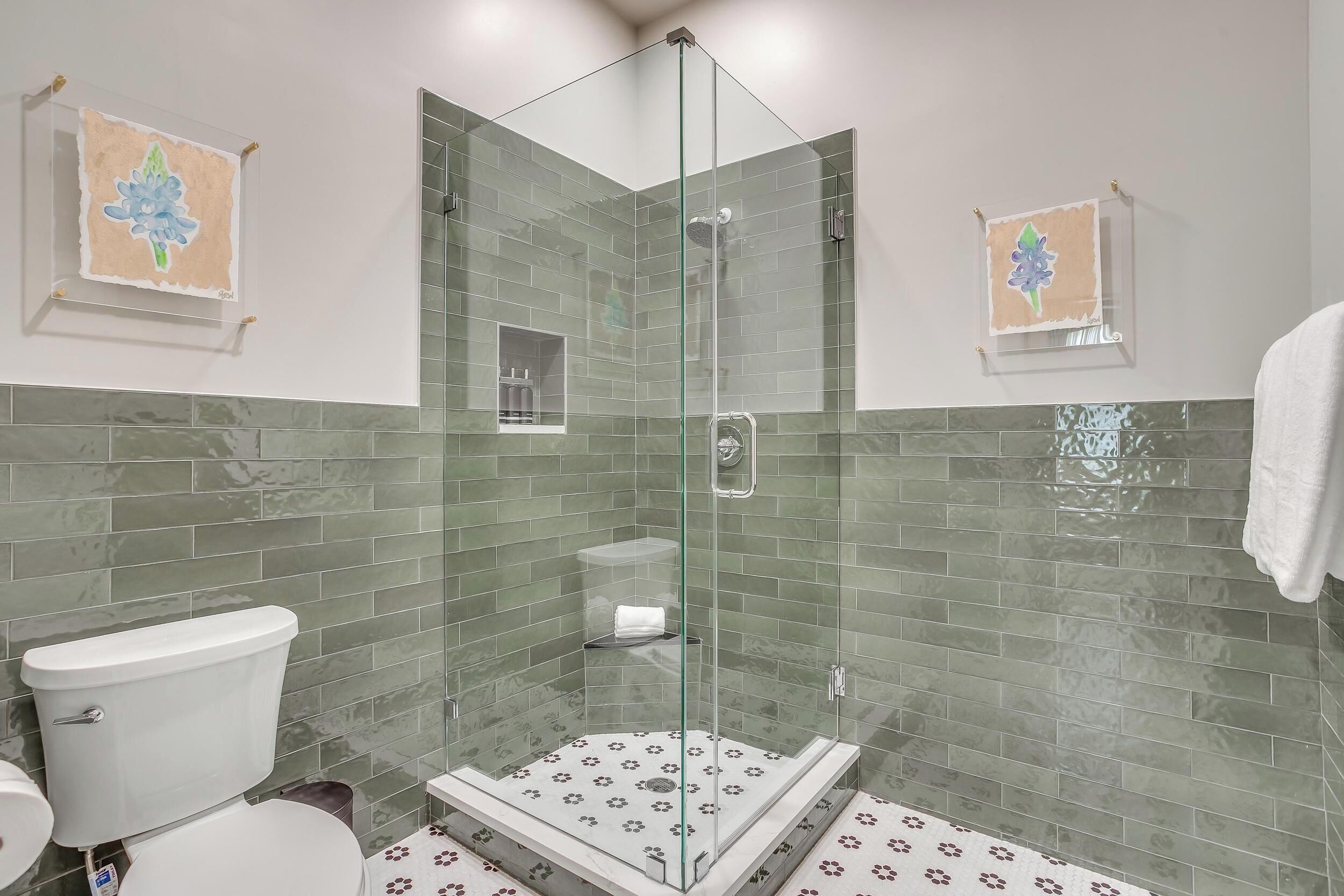 A bathroom with a glass-enclosed shower, a toilet, and a sink.