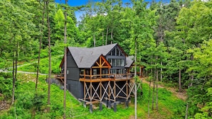 Een chalet met balkon, omringd door dicht bos.