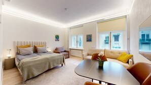 A modern, well-lit bedroom with a bed, bedside table, and a sofa.