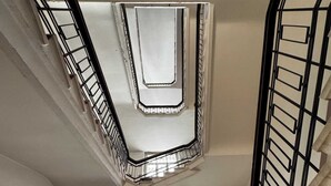 A view of a staircase with a metal railing, a window, and a ceiling with a light fixture.