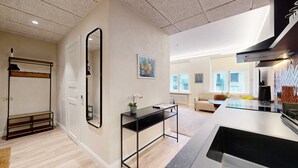 A modern kitchen with a large island, a dining area with a sofa, and a hallway with a mirror and artwork.