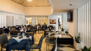 Un espace de restauration moderne, avec des tables dressées pour les clients, un lustre et une vue sur le restaurant en arrière-plan.