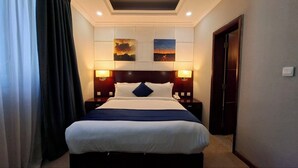 Une chambre d’hôtel avec un lit, deux lampes fixées au mur, une table de chevet et une porte.