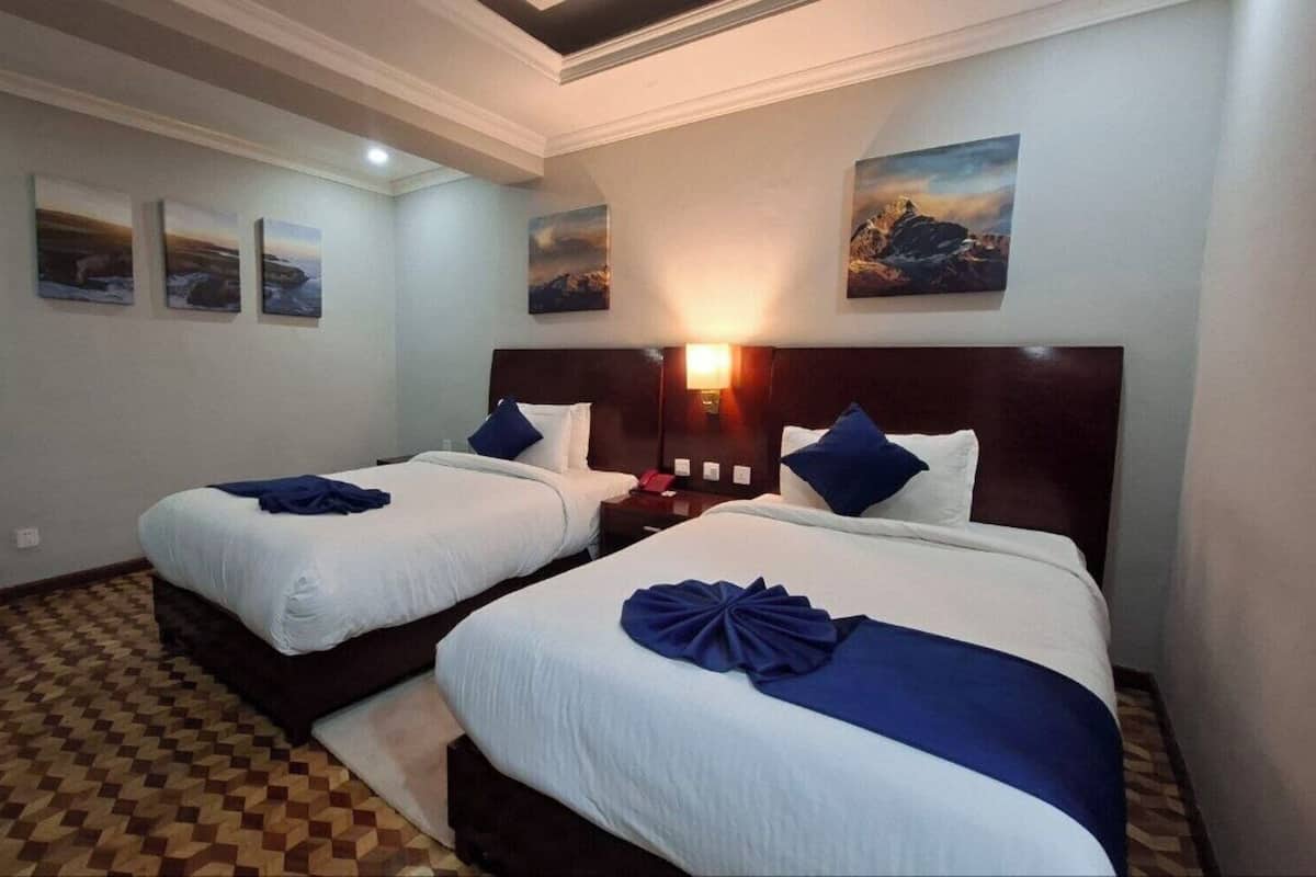 A hotel room with two beds, a checkered floor, and wall-mounted artwork.