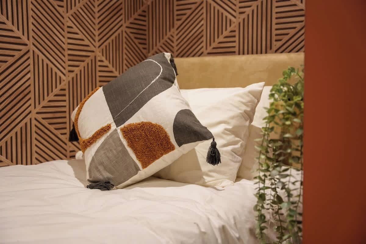 Ein Bett mit einem Kopfschild mit geometrischem Muster und einem Zierkissen.