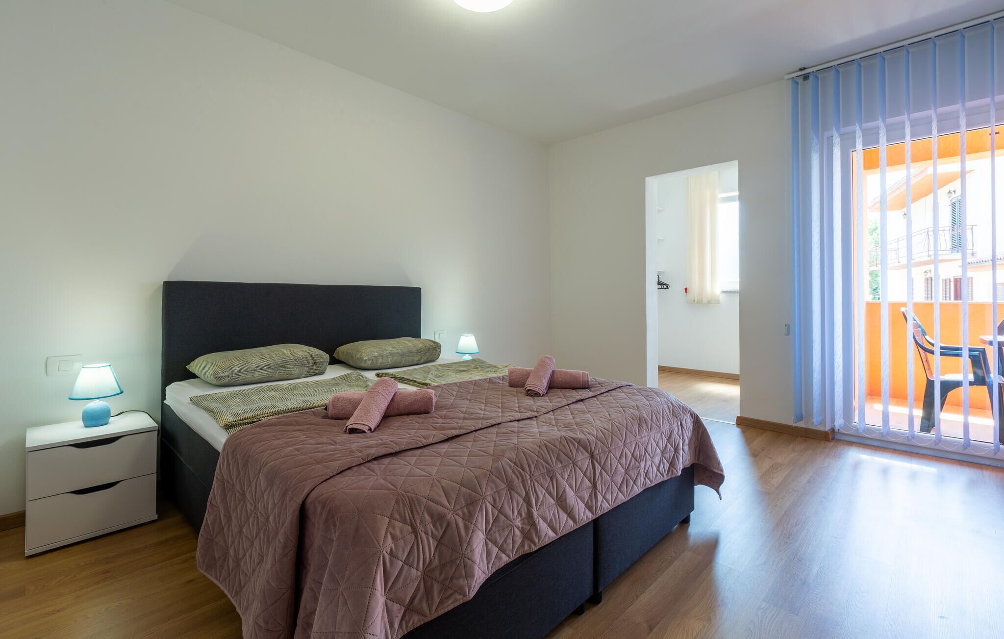 Un dormitori amb un llit, fallegueres i vista a un espai exterior.