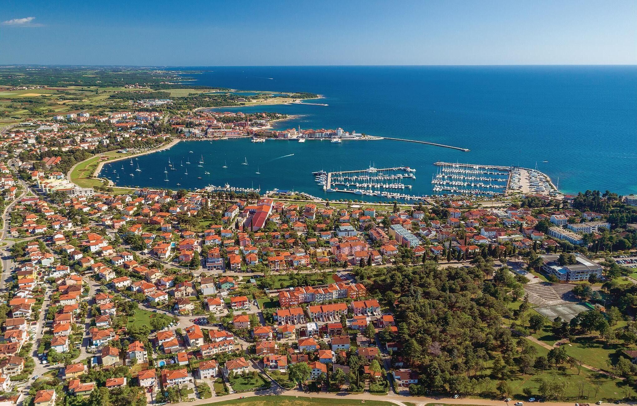 Eine Luftaufnahme einer Küstenstadt mit einem Yachthafen, Wohngebieten und freiem Blick auf das Meer.