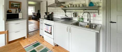A modern kitchen with white cabinets, a built-in oven, a sink, and a coffee maker.