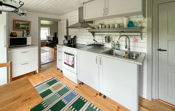 A modern kitchen with white cabinets, a built-in oven, a sink, and a coffee maker.