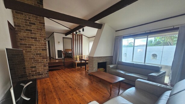 Una sala de estar con chimenea, piso de madera, un sofá y un televisor.