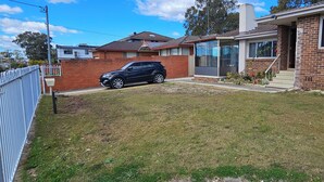 Una casa residencial con fachada de ladrillo, patio delantero y un SUV negro estacionado.