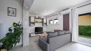 Una sala moderna con un sofá gris, un televisor de pantalla plana y una mesa de centro de madera.