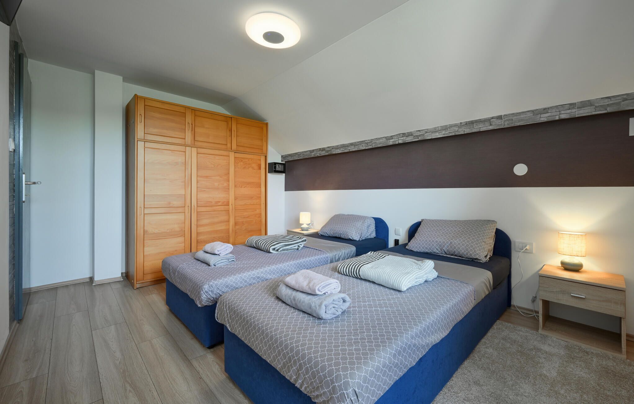 Ein Hotelzimmer mit zwei Betten, einem Holzschrank und einer Wand mit Steinverkleidung.
