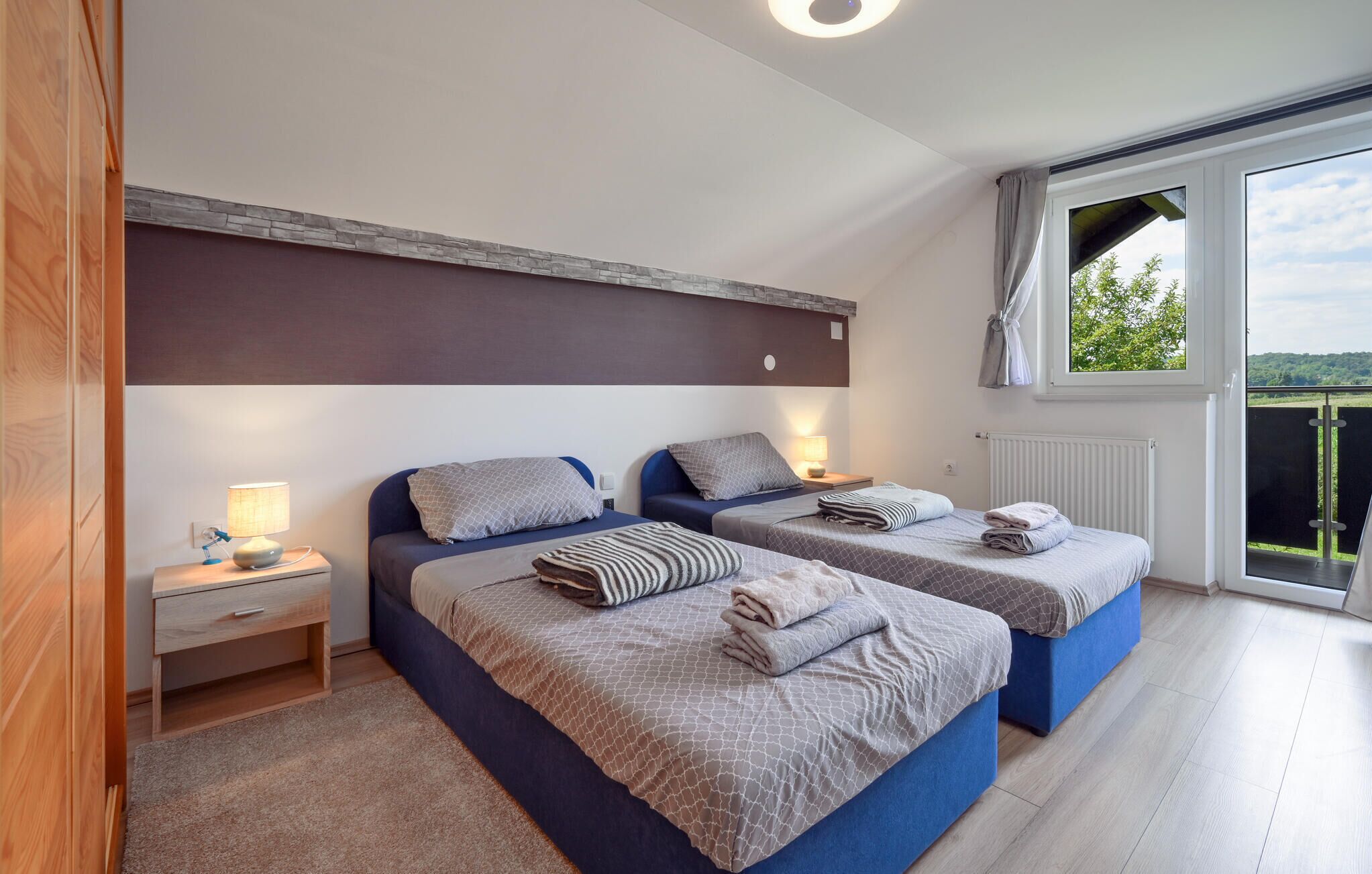 Une chambre avec deux lits, une table de chevet, une fenêtre donnant sur un paysage agréable et un plancher en bois.