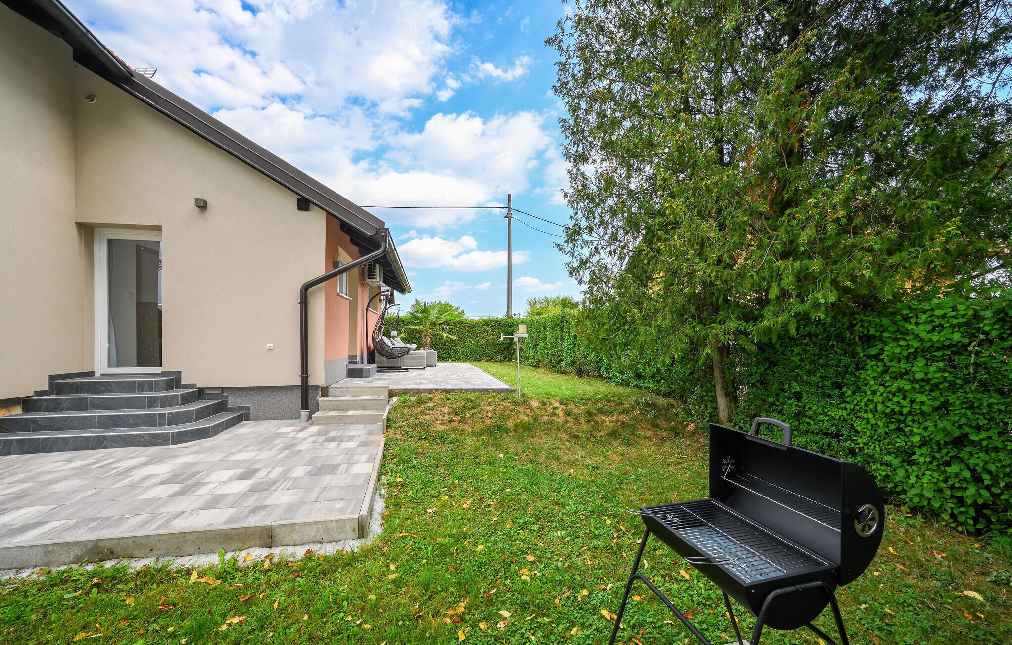 A modern building with a flat roof, a concrete patio, and a black grill.