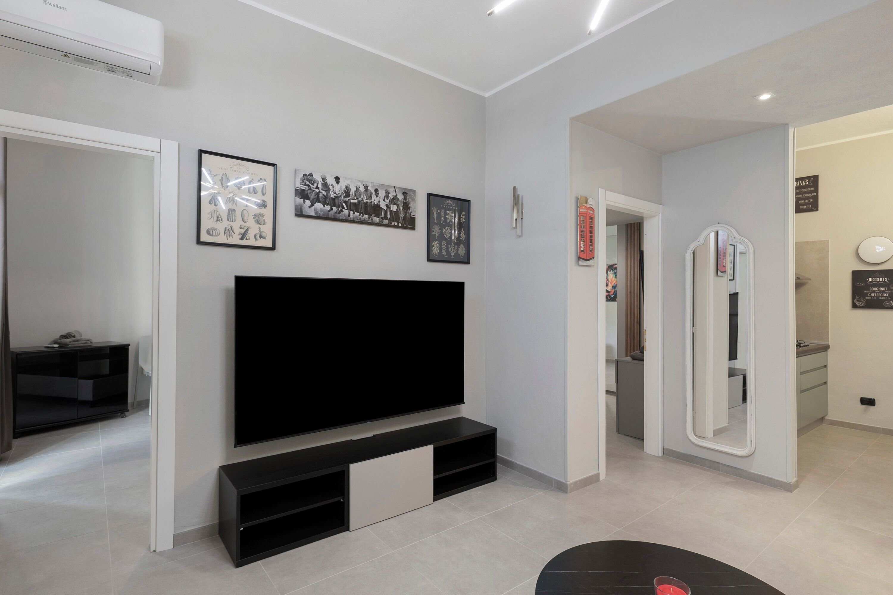 A modern living room with a flat-screen TV, a black entertainment unit, and a mirror.