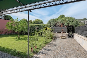 Ein Innenhof mit einem gepflasterten Weg, einer Pergola und einem Tor zu einem Gebäude.