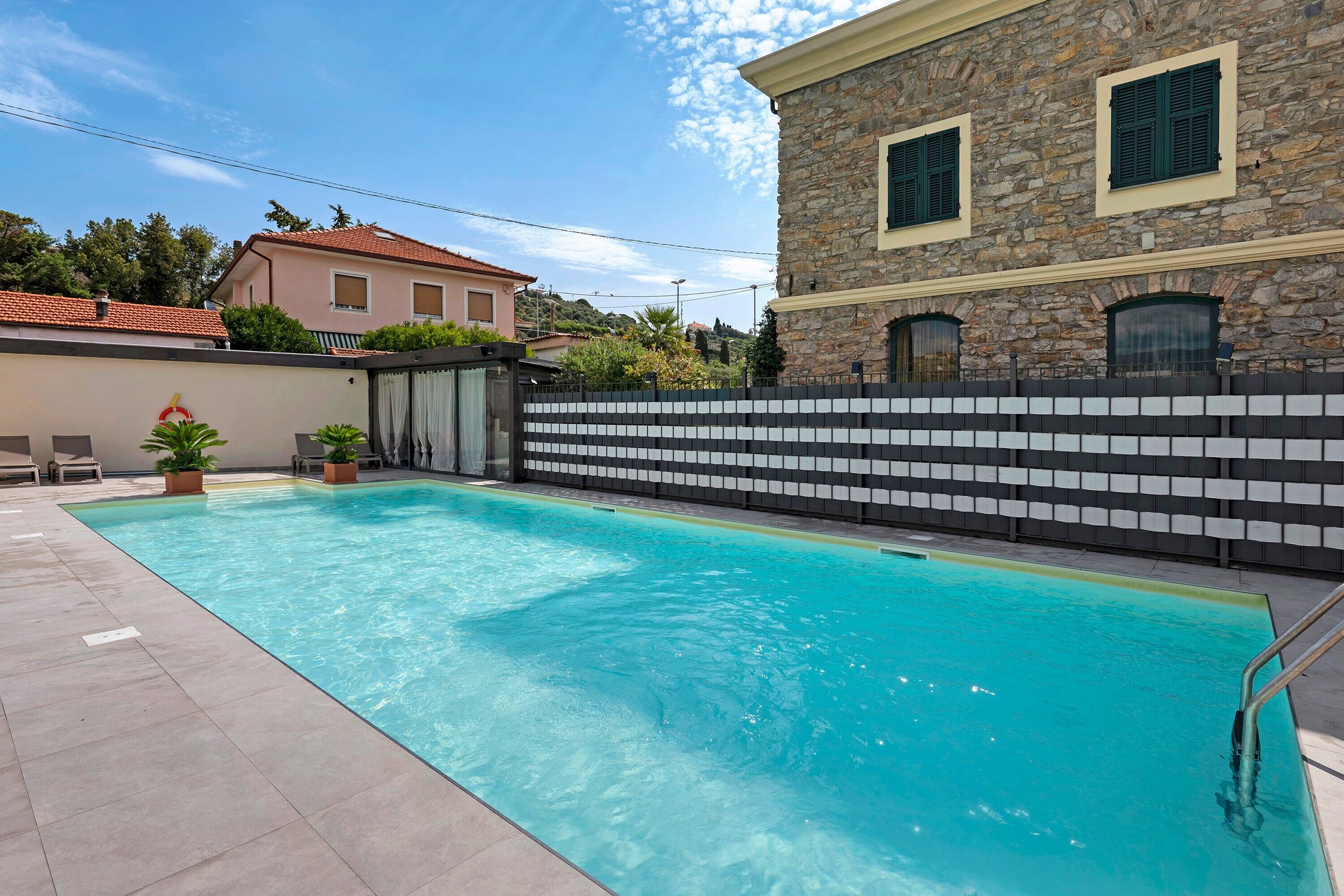 A swimming pool with a stone wall and a tiled deck.