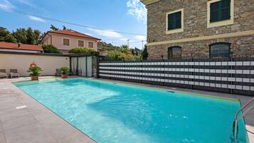 A swimming pool with a stone wall and a tiled deck.