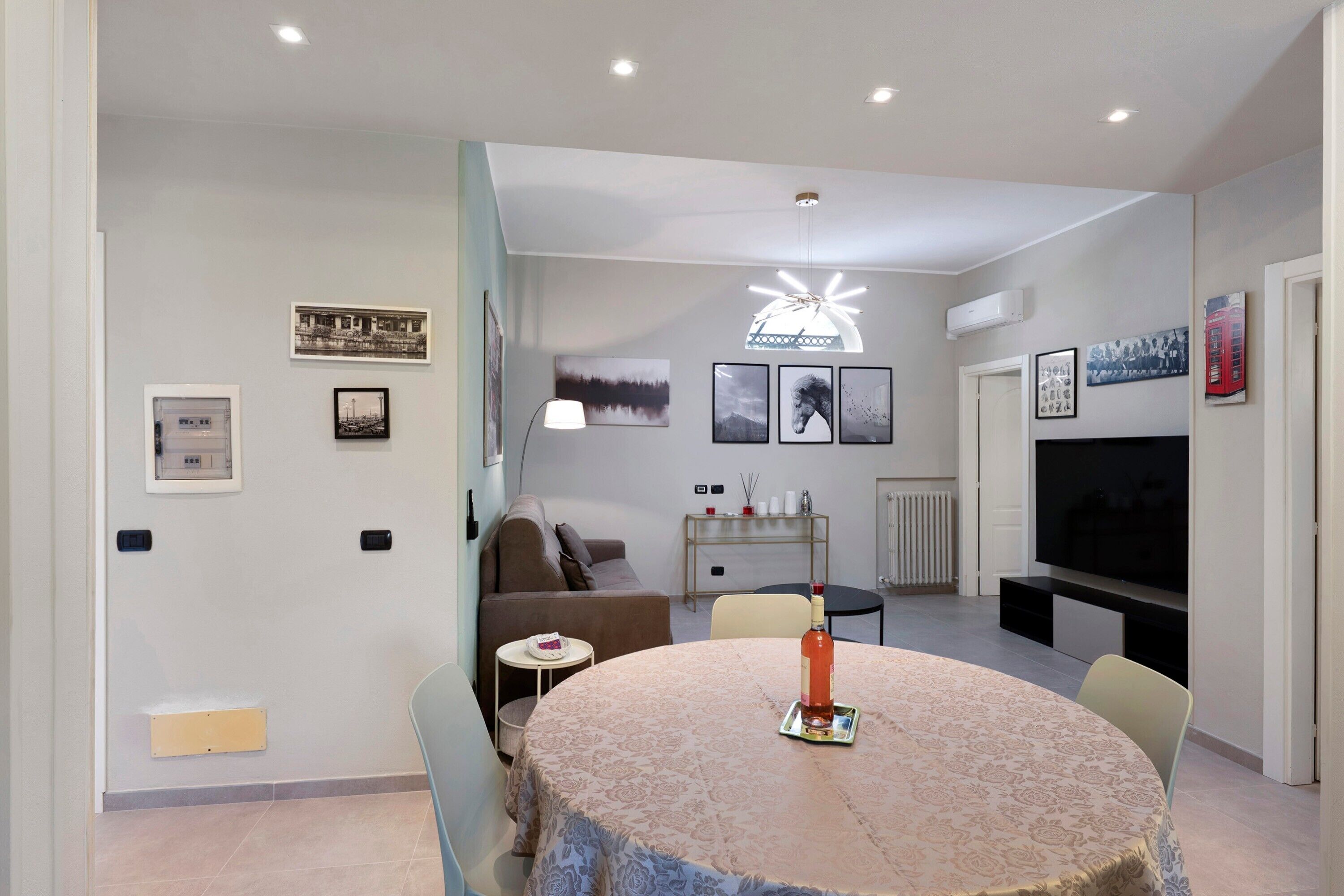A living room with a round table, a sofa, a TV, and various wall decorations.