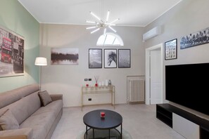 Ein Wohnzimmer mit Sofa, Couchtisch, Fernseher und Wandbildern.