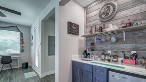Une cuisine moderne dotée d’un réfrigérateur encastré, d’un mur d’accent en bois et d’un coin bar avec diverses bouteilles et verres.