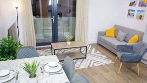 A modern living room with a grey sofa, yellow cushions, and a dining table set for four.