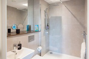 A modern bathroom with a glass-enclosed shower, a sink, and a mirror. - 3 Bed Flats near Station & City Centre - Sleeps 6 (Leeds)