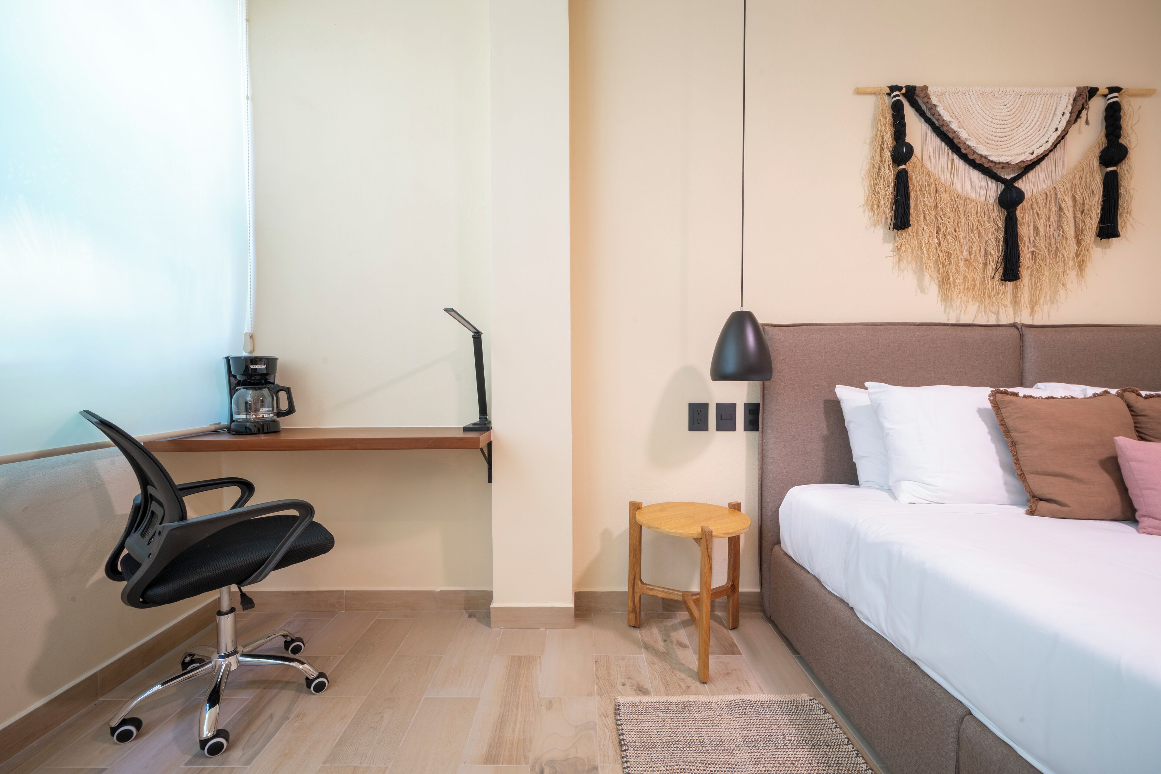Une chambre à coucher comprenant un lit, un bureau avec une chaise, une petite table et une lampe fixée au mur.