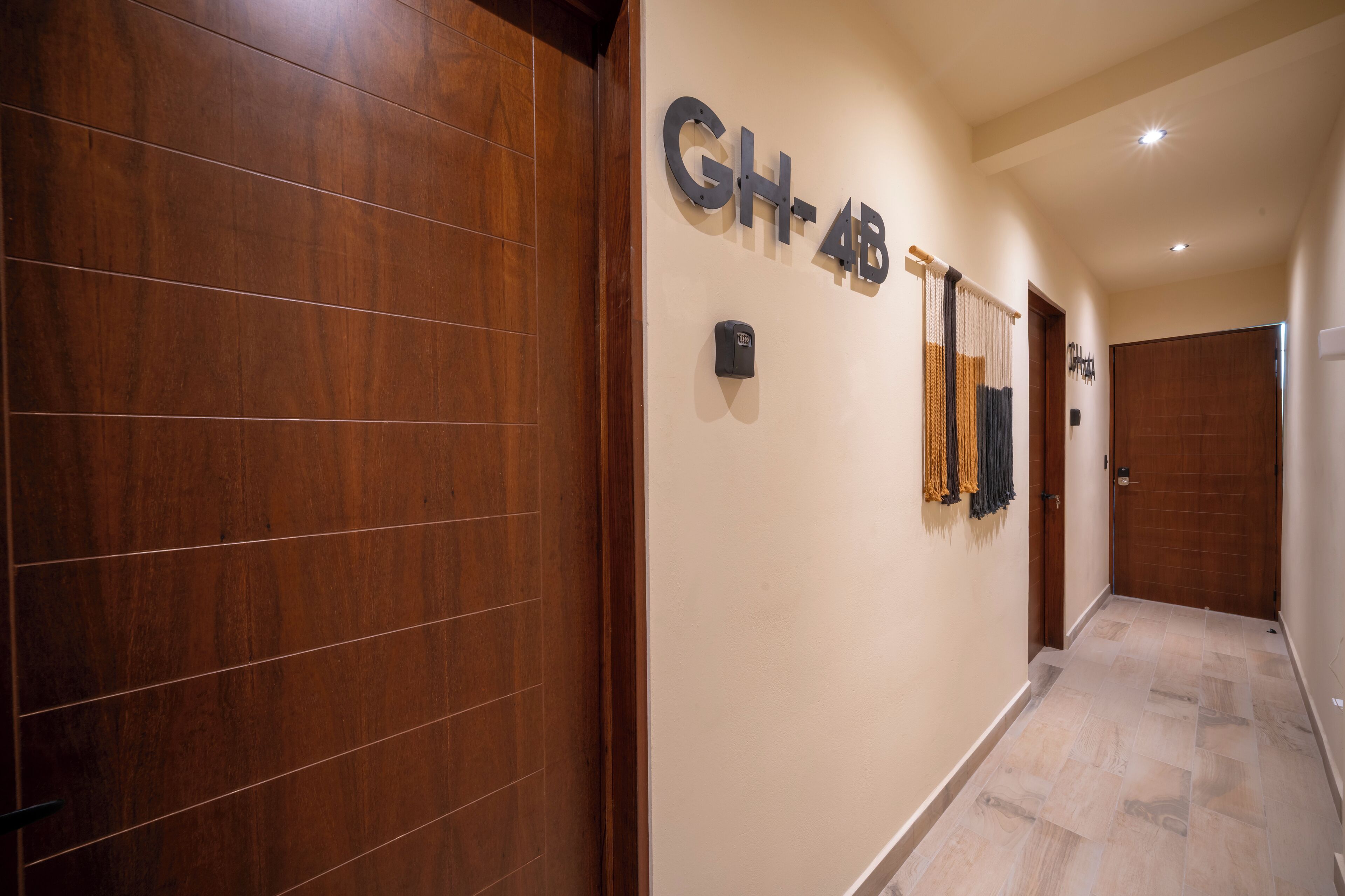 Un couloir aux murs recouverts de lambris en bois, une plaque fixée au mur indiquant « GH-4B », et une porte au fond.